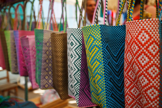 Colorful handwoven tote bags made from sustainable materials, showcasing ethical fashion and artisanal craftsmanship at a local market.
